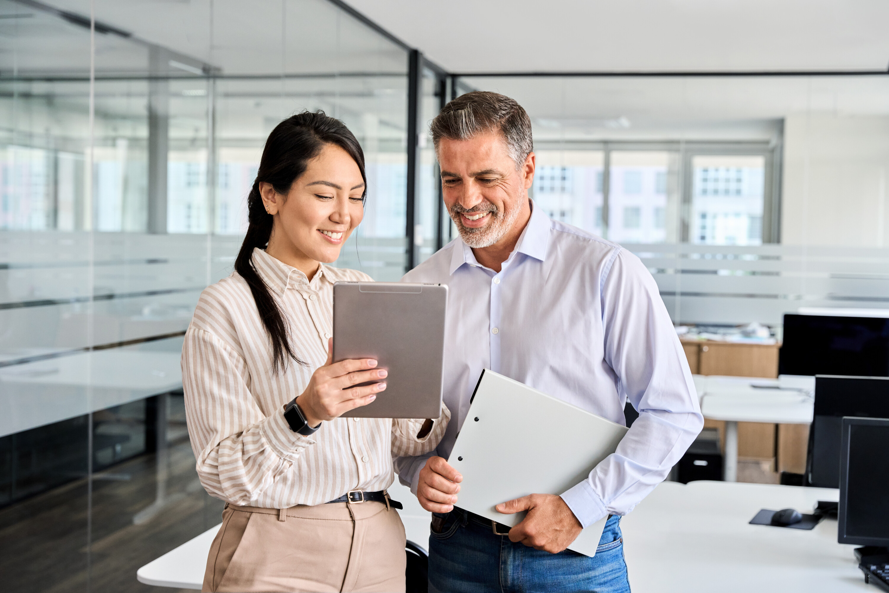 Two happy professional business people workers using digital tablet in office.