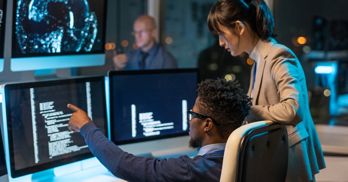 Confident businessman pointing at coded data on computer screen